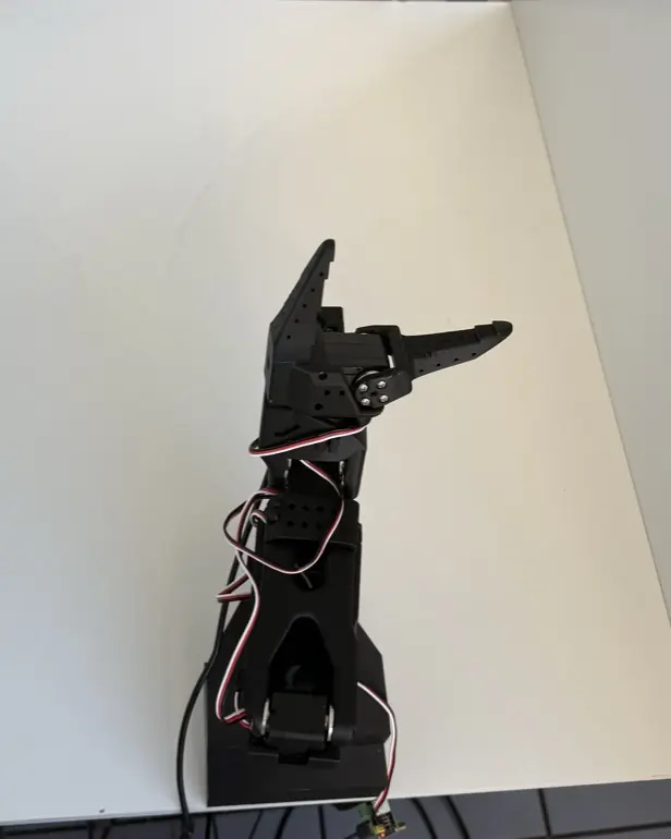 Phone photo of our setup from above: SO-100 arm on a white board